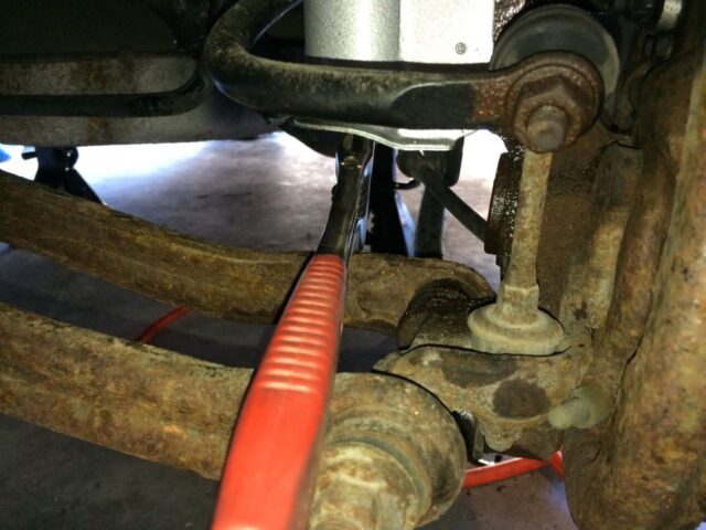 Holding the strut up in place with a crescent wrench