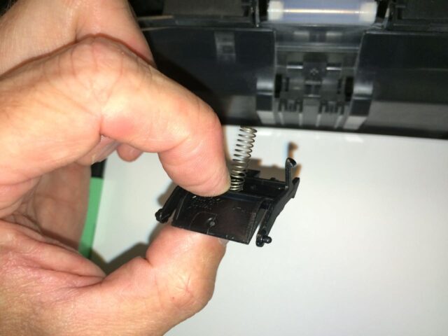 Hold the spring onto the new part with your fingernail
