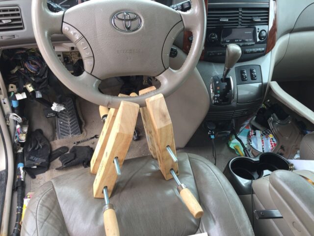 Using wood clamps, wedged against the seat, to hold the steering wheel straight