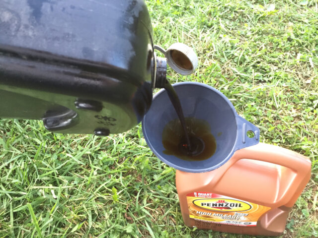 Pouring used oil from pan into empty bottle