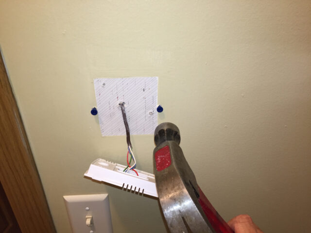 Tapping the anchors into the wall with a hammer