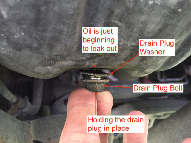 Holding the drain plug in place by hand